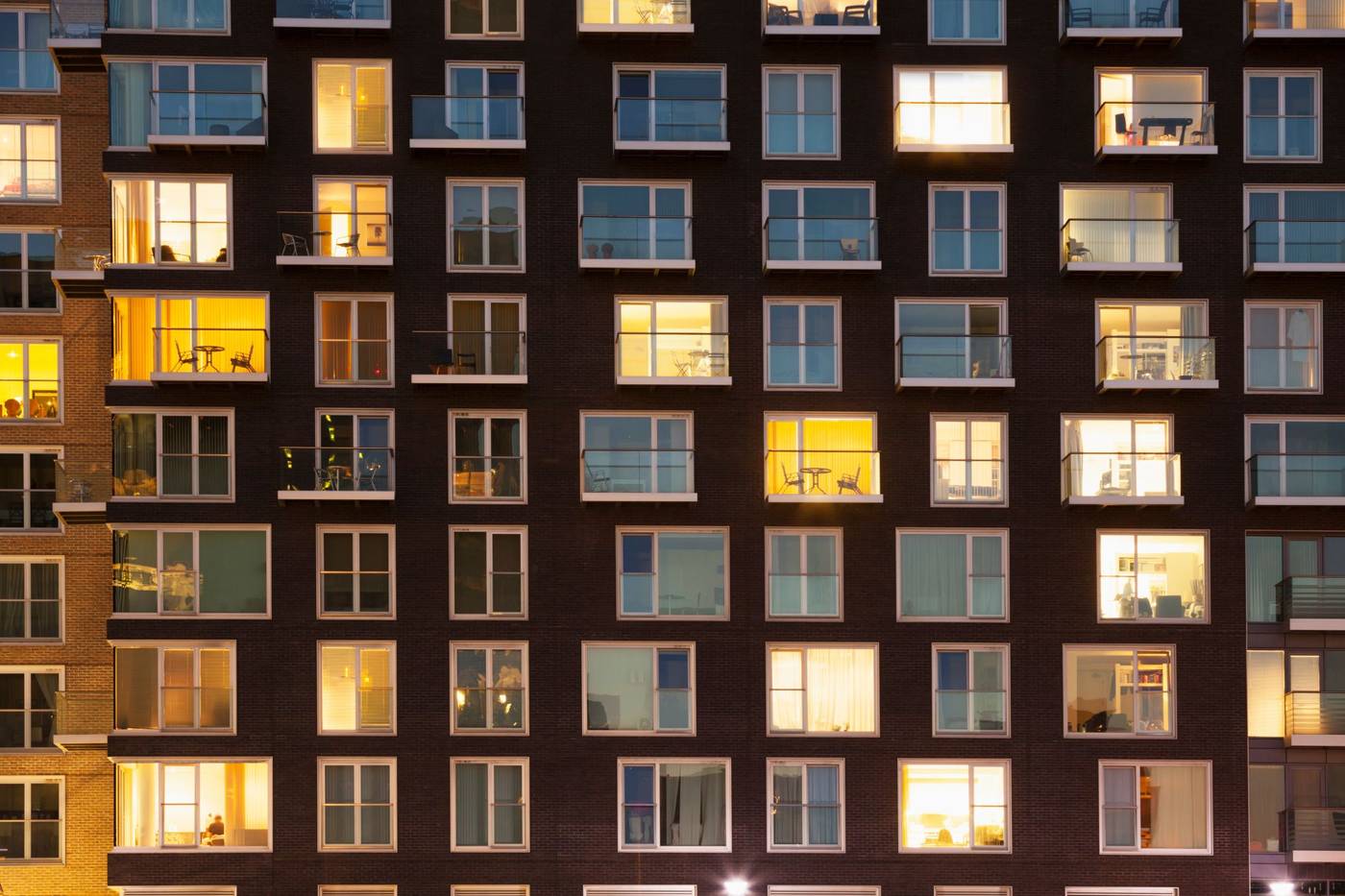 Flerbostadshus i skymningen med upplysta fönster och balkonger